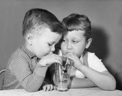 Close-up of a Boy and His Sister Sharing a Glass of Juice Stretched Canvas - (24 X 36)